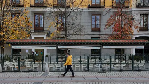 Una persona pasea al lado de una mampara instalada en un restaurante de la Plaza de Oriente, en Madrid (Espa&ntilde;a), a 12 de noviembre de 2020.