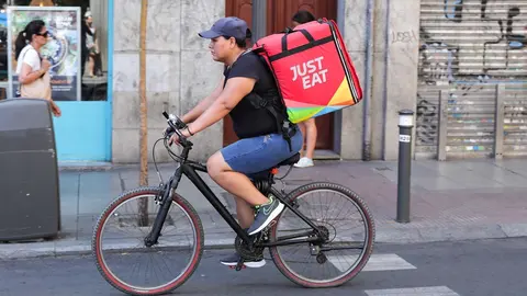 Fotograf&iacute;a de un repartidor de la empresa de reparto Just Eat transitando en bicicleta por una calle del centro de Madrid.