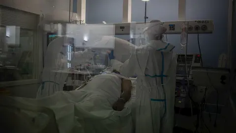 Trabajadores sanitarios protegidos atienden a un paciente en la UCI