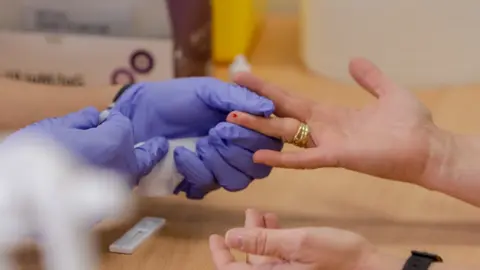 Personal sanitario de Cruz Roja saca sangre de un dedo a una persona para realizar el test r&aacute;pido de detecci&oacute;n de anticuerpos IgG e IgM en el Instituto de Formaci&oacute;n Integral en Seguridad y Emergencias (IFISE), en Colmenar Viejo, Madrid, a 2 de septiembre