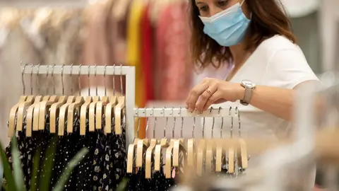 Mujer con mascarilla en una tienda de ropa.