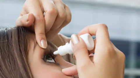 Woman using eye drop, eye lubricant to treat dry eye or allergy