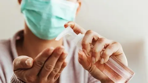 Close-up of woman using antibacterial hand gel at home. 
