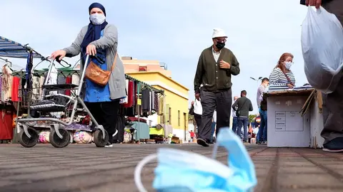 Una mascarilla quir&uacute;rgica en el suelo mientras varias personas caminan.