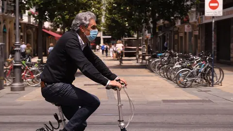 Un hombre pasea en bicicleta con mascarilla por una c&eacute;ntrica calle de Vitoria-Gasteiz, &Aacute;lava, Pa&iacute;s Vasco (Espa&ntilde;a).