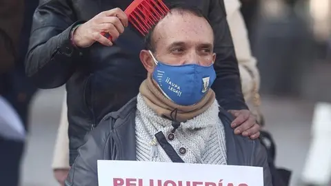 Un peluquero peina a un hombre durante una concentraci&oacute;n frente al Congreso de los Diputados
