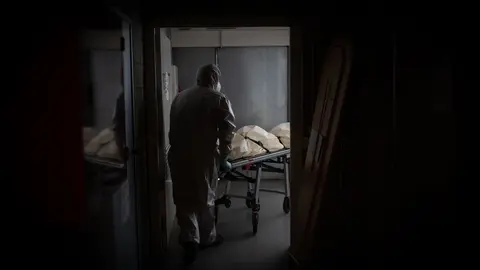 Un operario del Crematorio de Girona totalmente protegido traslada un ata&uacute;d de una v&iacute;ctima con Covid-19 a una c&aacute;mara frigor&iacute;fica para desinfectarlo antes de introducirlo en el horno crematorio. En Girona, Catalu&ntilde;a, (Espa&ntilde;a), a 6 de mayo de 2020.