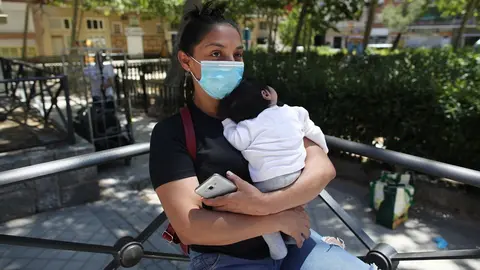 Luc&iacute;a, una mujer con su beb&eacute; en brazos, acude a las puertas de la Parroquia Santa Mar&iacute;a Micaela para recibir una ayuda alimentaria durante el d&iacute;a en el que el Gobierno ha aprobado en un Consejo de Ministros Extraordinario el ingreso m&iacute;nimo vital que prete