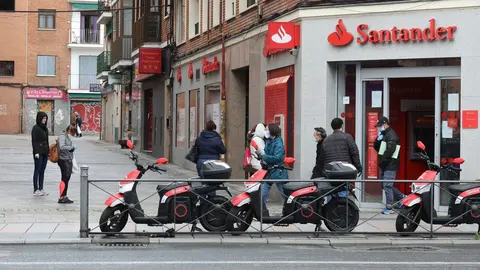 Varias personas esperan para entrar a una oficina del Banco Santander durante el inicio de la cuarta semana del estado de alarma decretado a consecuencia del coronavirus. En Madrid (Espa&ntilde;a), a 6 de abril de 2020.
