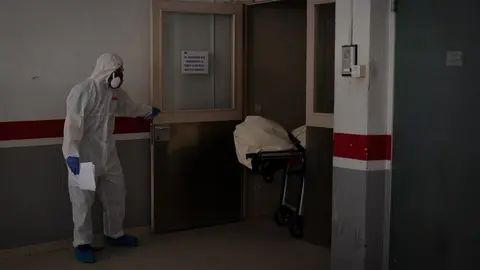 Varios operarios protegidos de los Servicios Funerarios Memora trasladan el cuerpo de una persona fallecida en una residencia de ancianos de Girona durante la pandemia.