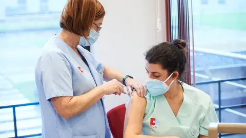 Un trabajadora sanitaria inyecta la segunda dosis de la vacuna de Pfizer-BioNTech contra la Covid-19 a una sanitaria del Hospital Universitario Marqu&eacute;s de Valdecilla