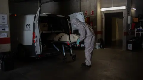Archivo - Varios operarios protegidos de los Servicios Funerarios Memora trasladan un cuerpo de una residencia  en la primera ola de la pandemia.