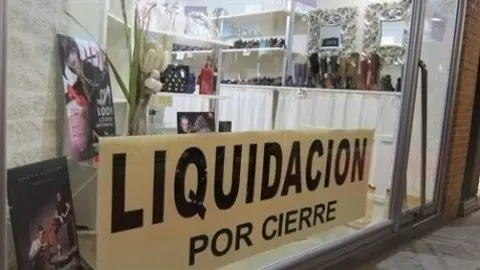 Archivo - Cartel liquidaci&oacute;n por cierre en un peque&ntilde;o comercio tradicional