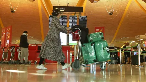 Una mujer camina con varias maletas en un carro en la terminal T4 del Aeropuerto Adolfo Su&aacute;rez Madrid-Barajas