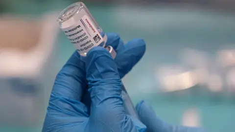 Una profesional sanitaria sostiene una jeringuilla con un vial de la vacuna contra la COVID-19 