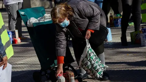 Una mujer recoge productos de alimentaci&oacute;n donados por parte de la Despensa Solidaria de Chamber&iacute; (Madrid) durante la concentraci&oacute;n y reparto de alimentos a familias vulnerables.