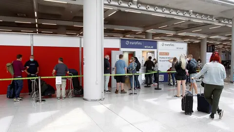 Pasajeros hacen cola para entrar al dispositivo de detecci&oacute;n de Covid-19.