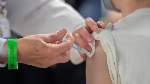 Una trabajadora sanitaria administra la primera dosis de la vacuna AstraZeneca contra el Covid-19 a una persona en el Wizink Center, a 9 de abril de 2021, en Madrid, (Espa&ntilde;a). El dispositivo, puesto en marcha este viernes por la Comunidad de Madrid y coor