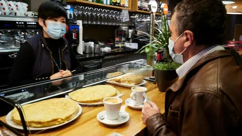 Archivo - Una camarera y un cliente en el interior de un bar. Archivo