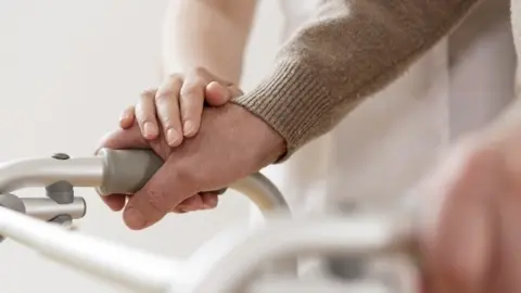 Archivo - Physiotherapist supporting disabled man