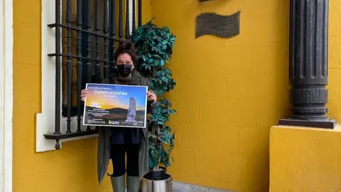 La concejala de Cultura de Torrelavega, Esther Velez, con el cartel de la exposici&oacute;n sobre las construcciones del hombre