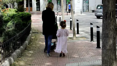 Archivo - Una mujer camina con su hija vestida de chulapa por el centro de la capital.