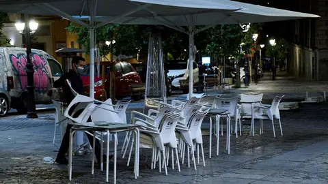 Una persona recoge la terraza de una cafeter&iacute;a 