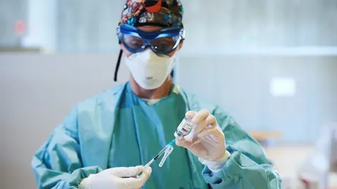 Archivo - Una profesional sanitaria sostiene un vial con la vacuna 