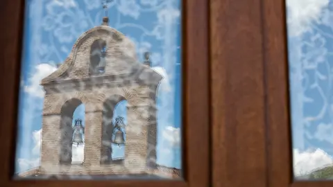 Reflejo de una iglesia en un cristal de una vivienda.