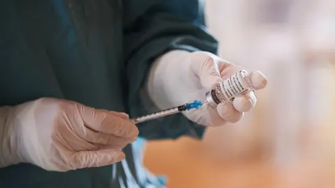 Archivo - Una profesional sanitaria sostiene un vial con la vacuna