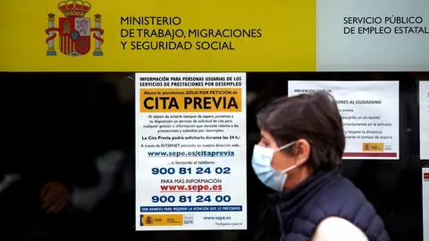 Archivo - Una mujer pasa por la puerta de una oficina de empleo, SEPE 