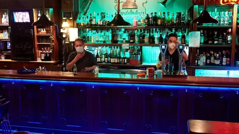 Dos camareros en un local de ocio nocturno, antes de su cierre a medianoche,