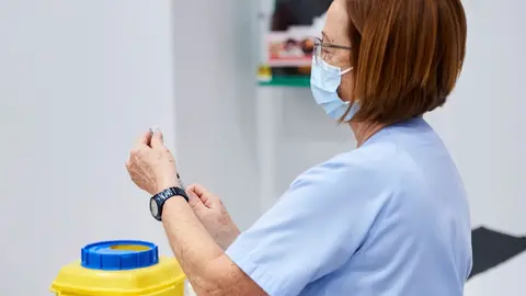 Archivo - Una trabajadora sanitaria sostiene una jeringuilla 