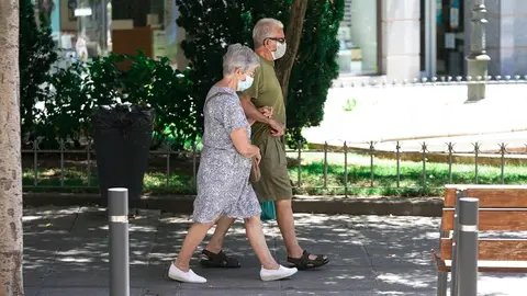 Una pareja de ancianos con mascarilla camina por la calle cogida del brazo, a 27 de julio de 2021, en Madrid, (Espa&ntilde;a).