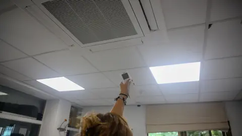 Una mujer enciende el aire acondicionado en una oficina.- Archivo