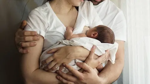  Father and mother with a newborn son. New young multi-generation family. Breast-feeding