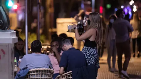 Archivo - Una camarera atiende a varias personas en la terraza de un bar 