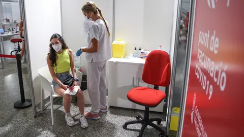 Una sanitaria vacuna a una adolescente con la primera dosis de la vacuna Moderna en la Ciudad de las Artes, a 16 de agosto de 2021, en Valencia, Comunidad Valenciana, (Espa&ntilde;a).