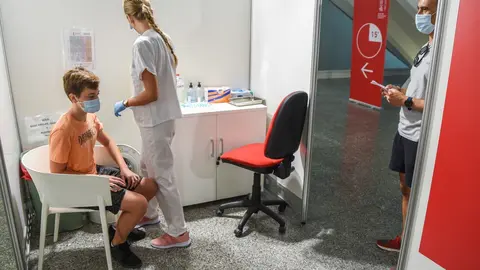 Una sanitaria vacuna a un adolescente con la primera dosis de la vacuna Moderna 