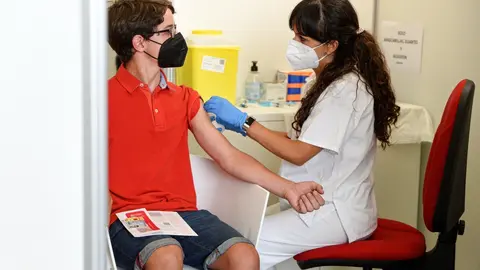 Una sanitaria vacuna a un adolescente con la primera dosis de la vacuna Moderna 