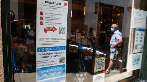 Archivo - Carteles en diferentes idiomas de indicaciones de obligatoriedad de presentar certificados antes de acceder al interior, en una marisquer&iacute;a de la Rua do Franco
