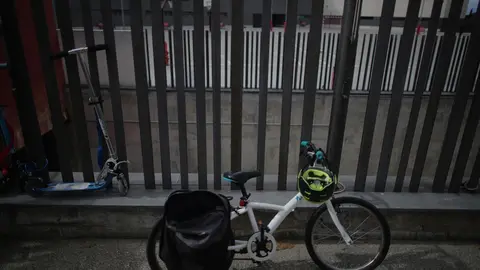 Archivo - Una bicicleta y un monopat&iacute;n se encuentran apoyados en una de las verjas de un colegio