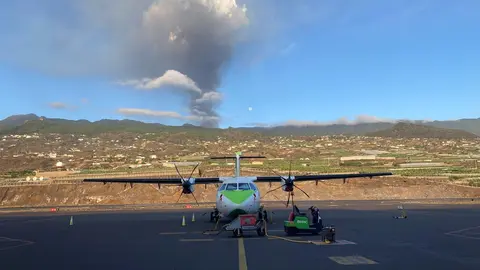 Un avi&oacute;n de Binter en la pista del aeropuerto de La Palma, con el volc&aacute;n en erupci&oacute;n al fondo