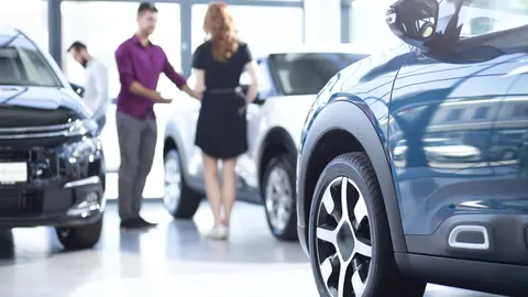 Low angle of exclusive car in a dealing salon with seller and buyer