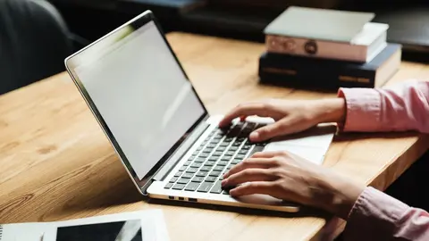 Close up portrait of male hands typing on laptop computer on a table indoors